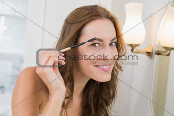 Portrait of a beautiful young woman applying mascara