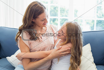 Mother embracing her happy daughter in living room