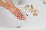 Close-up side view of washing hands at washbasin