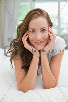 Portrait of a beautiful smiling young woman lying in bed
