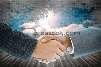 Composite image of business handshake against wall