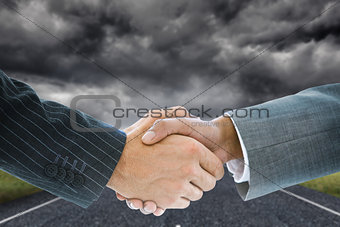 Composite image of business handshake against storm