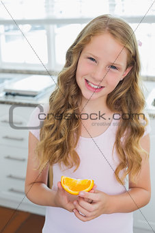 Smiling young girl with a sweetlime slice in kitchen