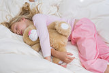 Girl sleeping peacefully with stuffed toy in bed