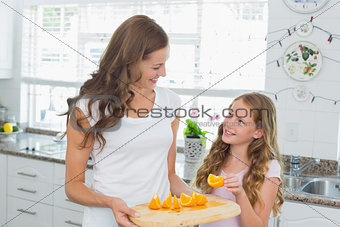 Mother looking at daughter as she picks a slice of sweet lime
