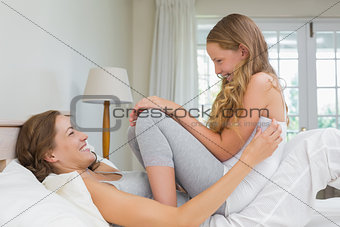 Happy woman and girl playing in the bedroom
