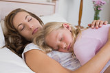 Young girl sleeping on mother in bed