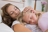 Young girl sleeping on mother in bed