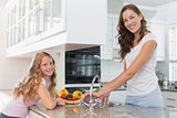 Girl helping her mother to wash vegetables in kitchen