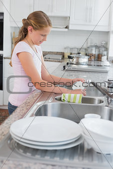 Side view of a girl washing utensils in kitchen