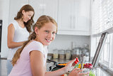 Girl helping mother to prepare food in kitchen