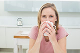 Relaxed woman having coffee in kitchen