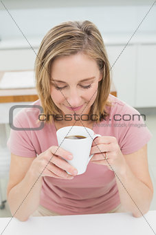 Eelaxed young woman having coffee in kitchen