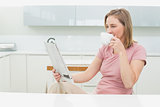 Woman reading newspaper while having coffee in kitchen