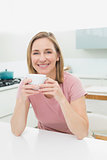 Relaxed smiling woman having coffee in kitchen