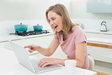 Smiling woman using laptop in kitchen