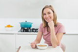 Smiling woman having cereals in kitchen