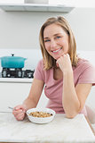 Smiling woman having cereals in the kitchen