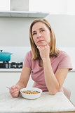 Thoughtful woman having cereals in kitchen