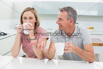 Relaxed couple with coffee cups in kitchen