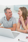 Cheerful couple using laptop in kitchen