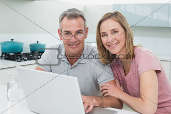 Portrait of a couple using laptop in kitchen