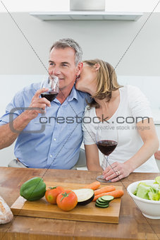 Loving couple with wine glasses in kitchen
