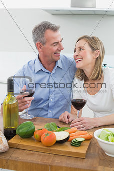 Cheerful couple with wine glasses in kitchen