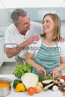 Happy couple preparing food together in kitchen