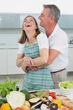 Side view of a man embracing woman in kitchen