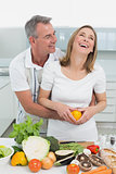 Cheerful couple preparing food together in kitchen