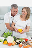 Cheerful couple preparing food together in kitchen