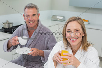 Smiling couple with orange juice and coffee in kitchen