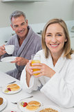 Smiling couple with orange juice and coffee in kitchen