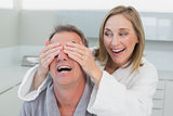 Close-up of a happy woman covering man's eyes