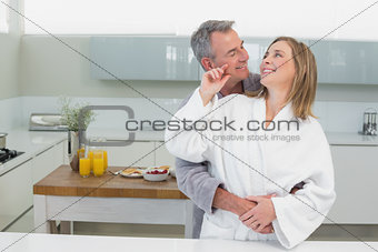 Man embracing woman from behind in kitchen