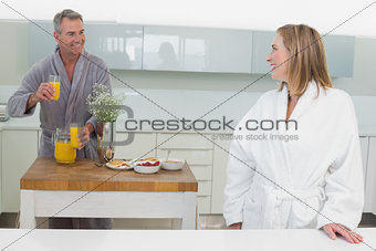 Smiling woman and man with orange juice in kitchen