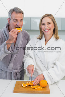 Happy couple cutting orange in kitchen