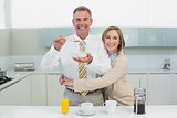 Woman embracing man while having breakfast in kitchen
