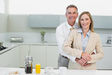 Businessman embracing woman from behind in kitchen