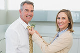 Woman adjusting businessman's tie in kitchen