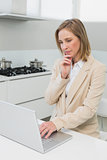Concentrated businesswoman using laptop in kitchen