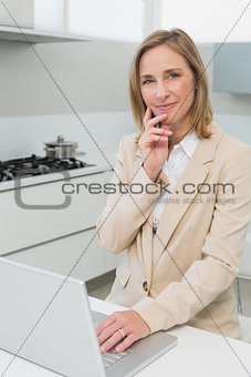 Portrait of a businesswoman using laptop in kitchen