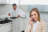 Businesswoman on call while man preparing food in kitchen