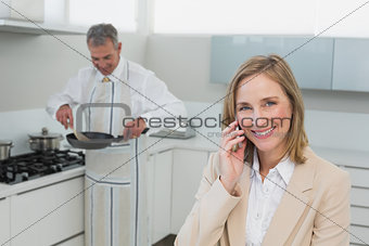 Businesswoman on call while man preparing food in kitchen