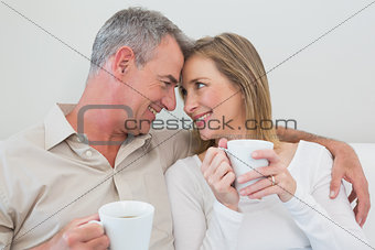 Loving couple with coffee cups in living room