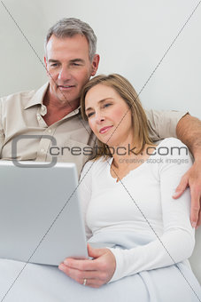 Loving couple using laptop on sofa