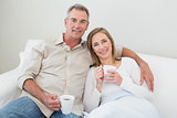 Relaxed couple with coffee cups in living room
