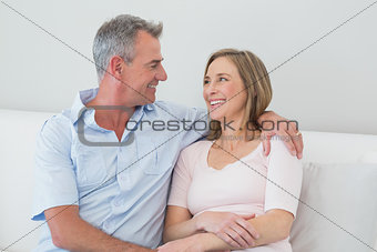 Relaxed couple sitting on sofa with arm around
