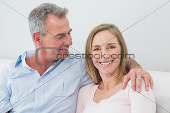 Relaxed couple sitting on sofa with arm around